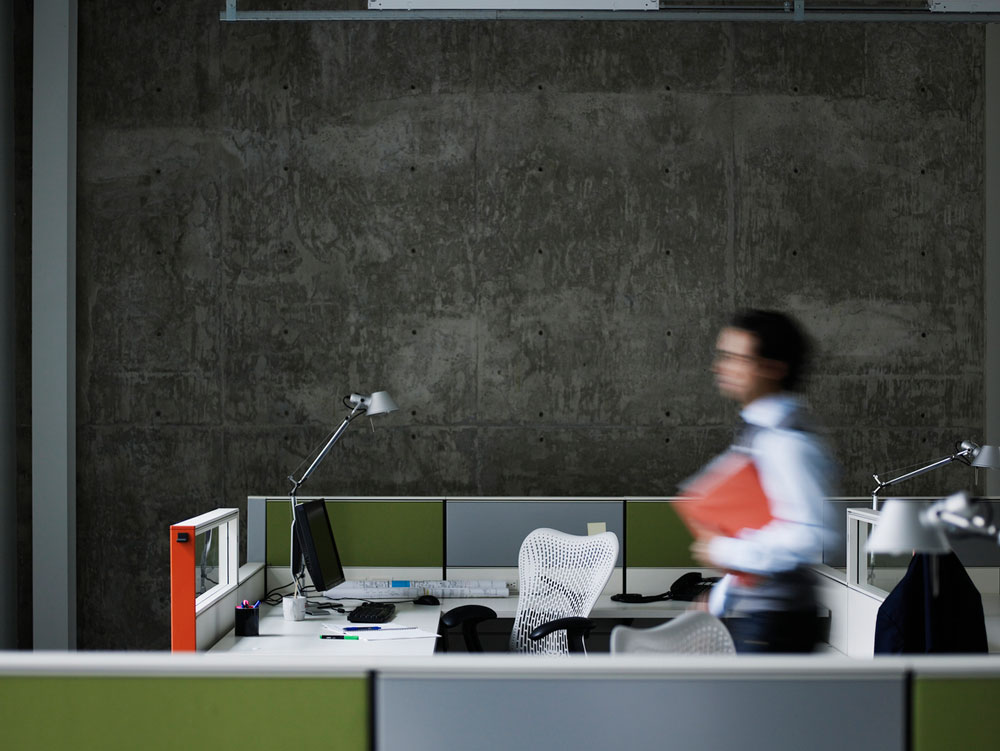 Man walking past desks with folders