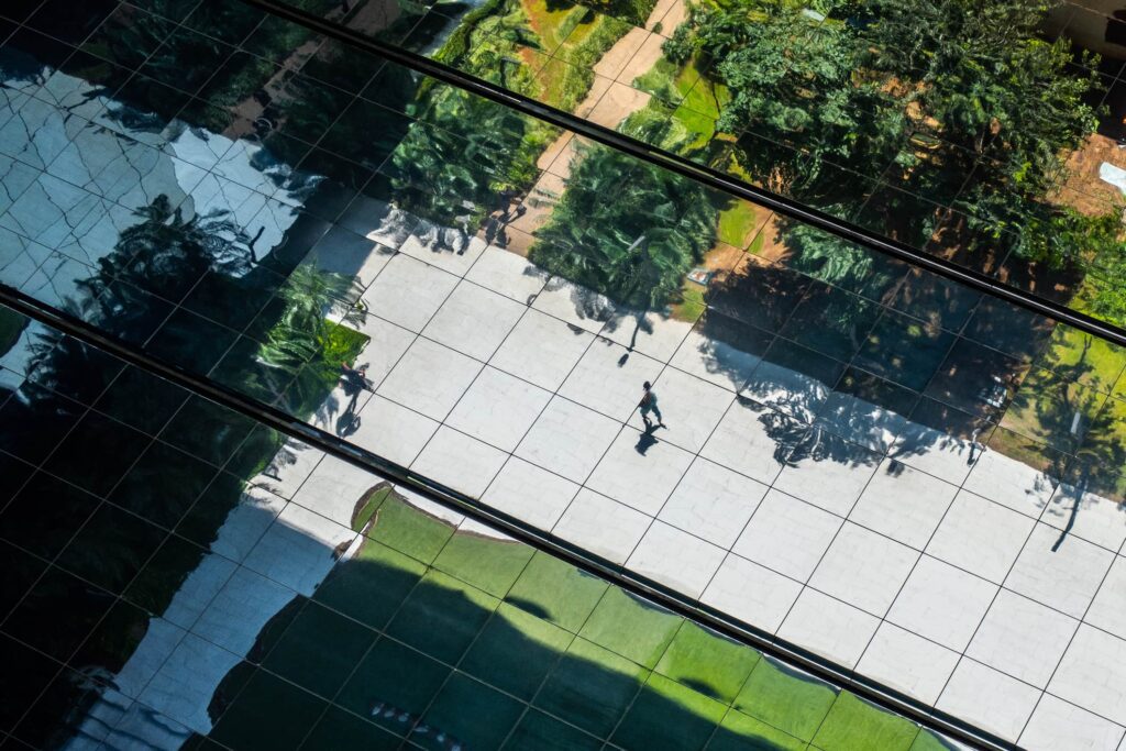 View of person walking on a path in the reflection of a building