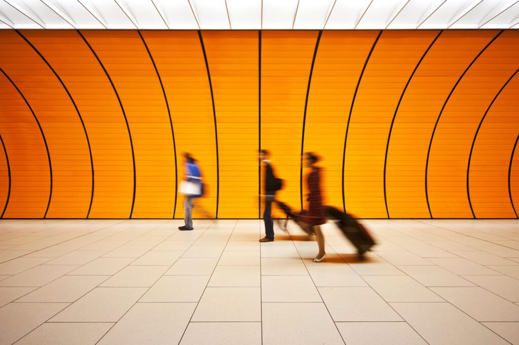 People walking through yellow tunnel with suitcases
