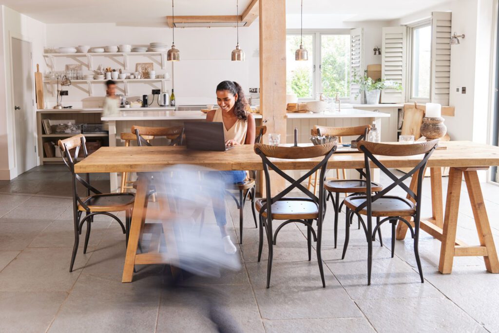 Mother working at home on laptop in kitchen