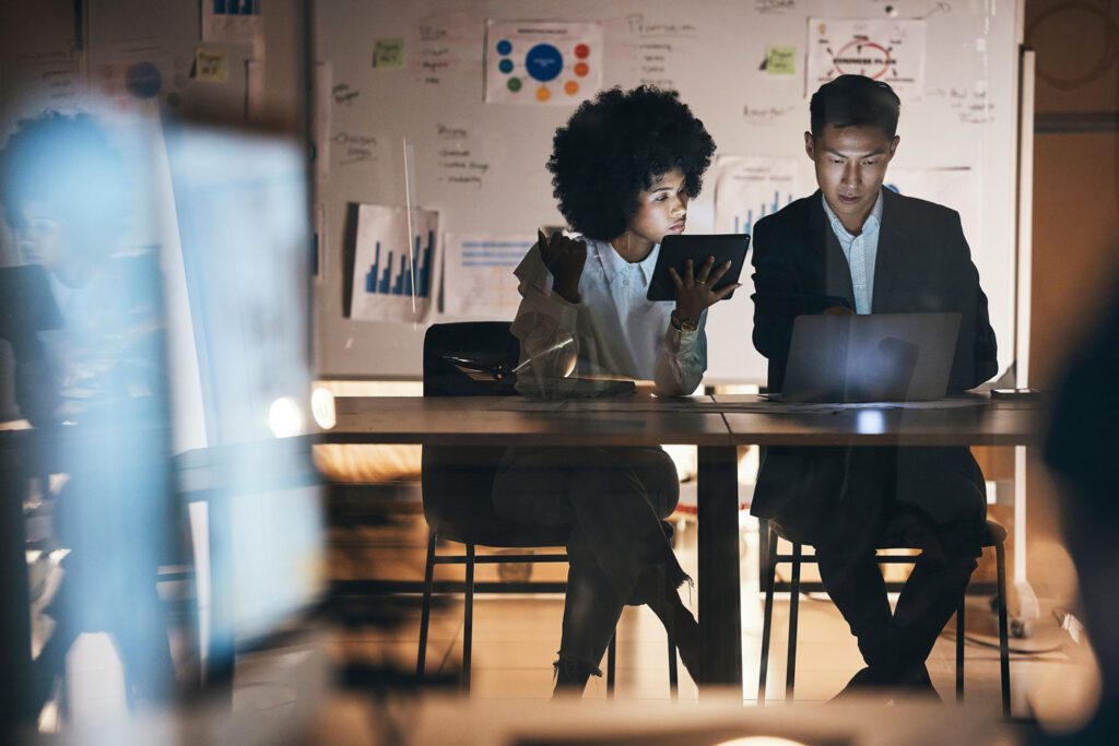 Two people sat in office with laptops