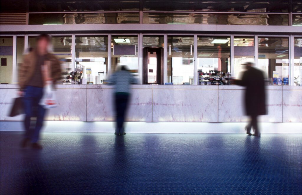 3 blurry people at a bank counter