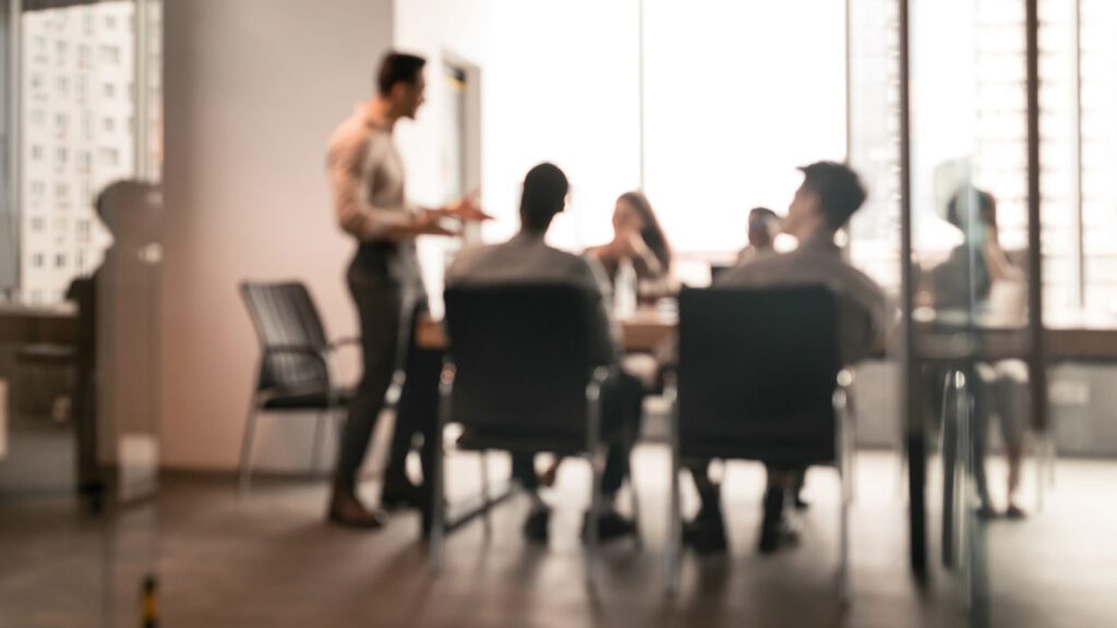 Businessman Giving Speech During Seminar With Coworkers In Office