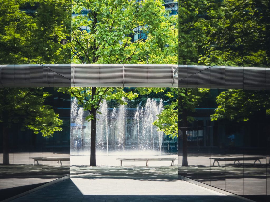 modern building and empty courtyard with bench and single tree