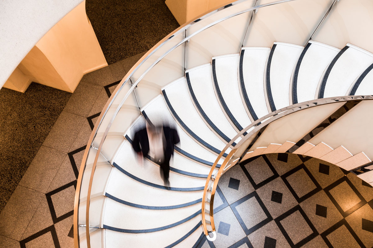 Overhead view depicting blurred motion of a business person walking down a spiral staircase.