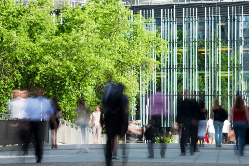 People walking away from building with trees. Long exposure