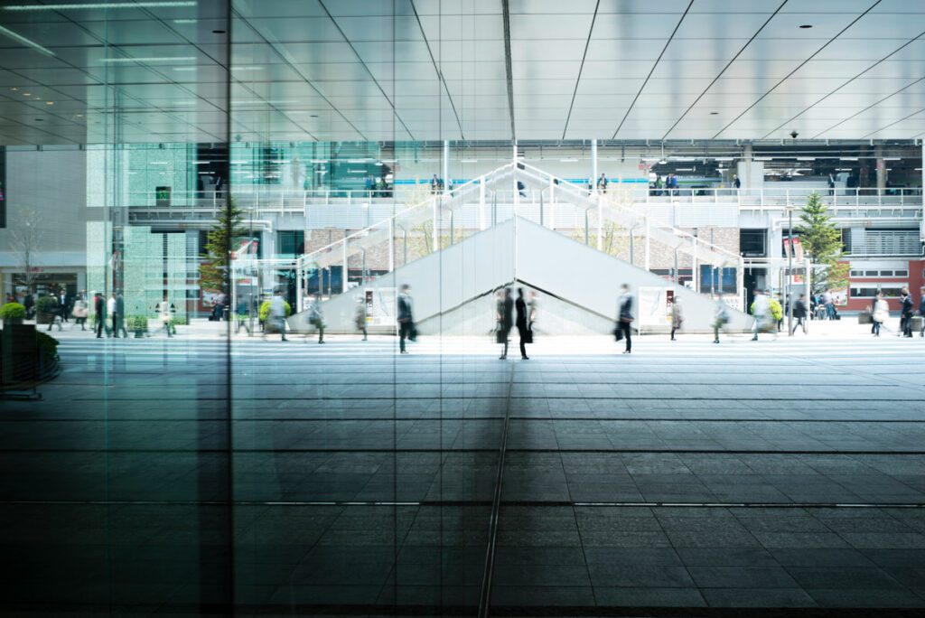 People walking past glass office buildings. Long exposure