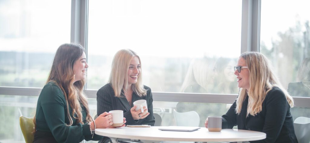 Co workers sat drinking coffee and smiling