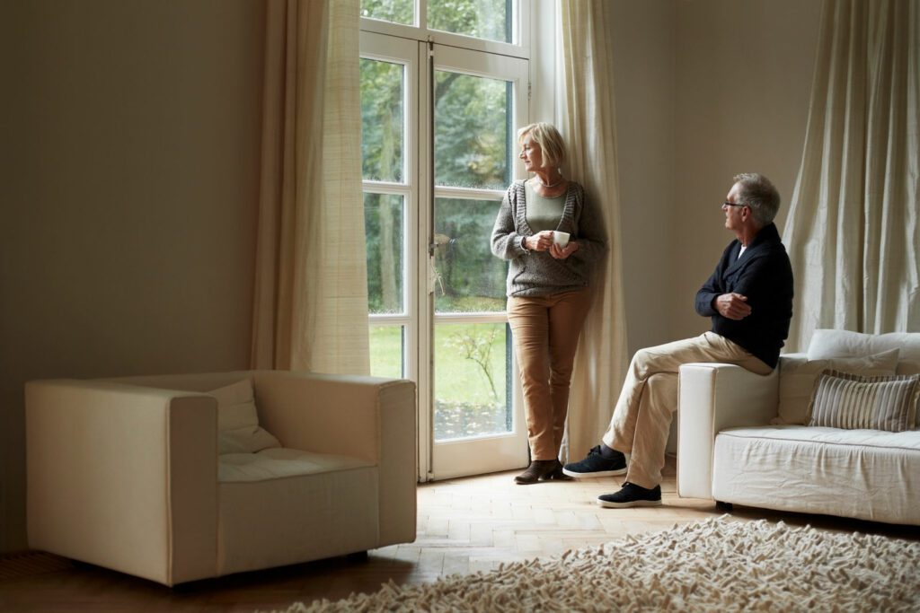 Senior couple looking out through house door