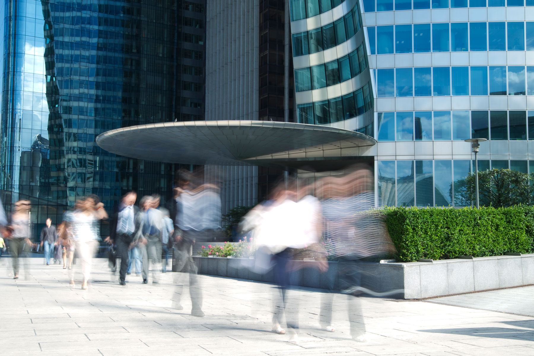 group of office workers rushing in front of a modern business building, long exposure