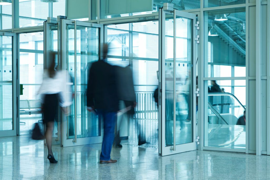 People Walking Through Entrance Door of Modern Building