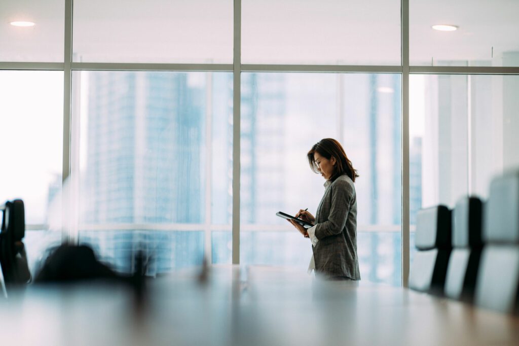 An investor holding digital tablet and look in distance window thinking or planning future success, thoughtful motivated mature businesswoman pondering over new ideas.