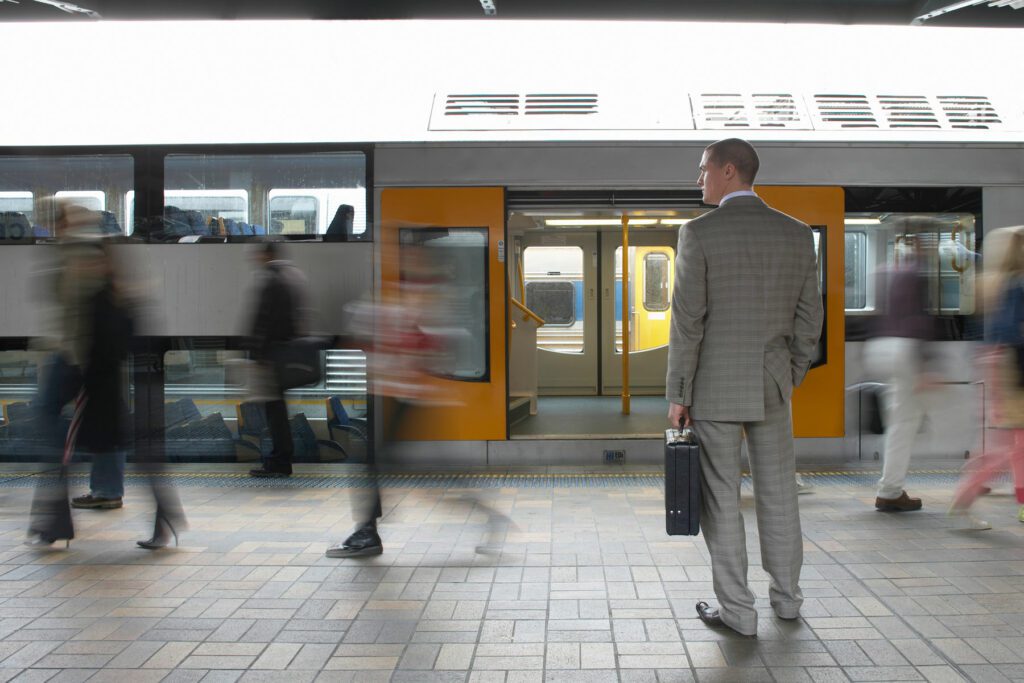 Commuters passing businessman on platform