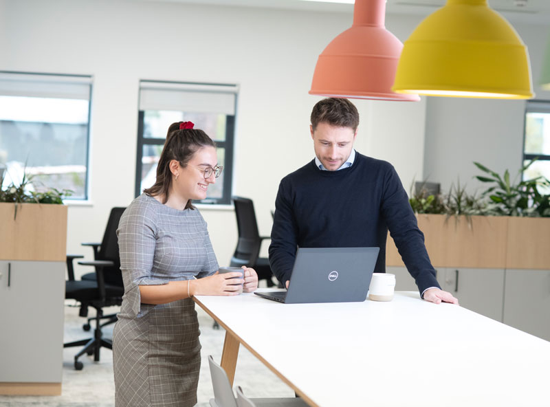 Two people looking at laptop in modern office