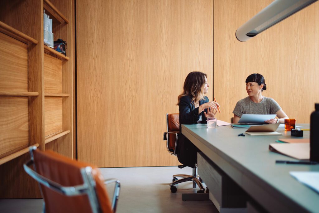 Two businesswomen engaged in a discussion at a modern office table