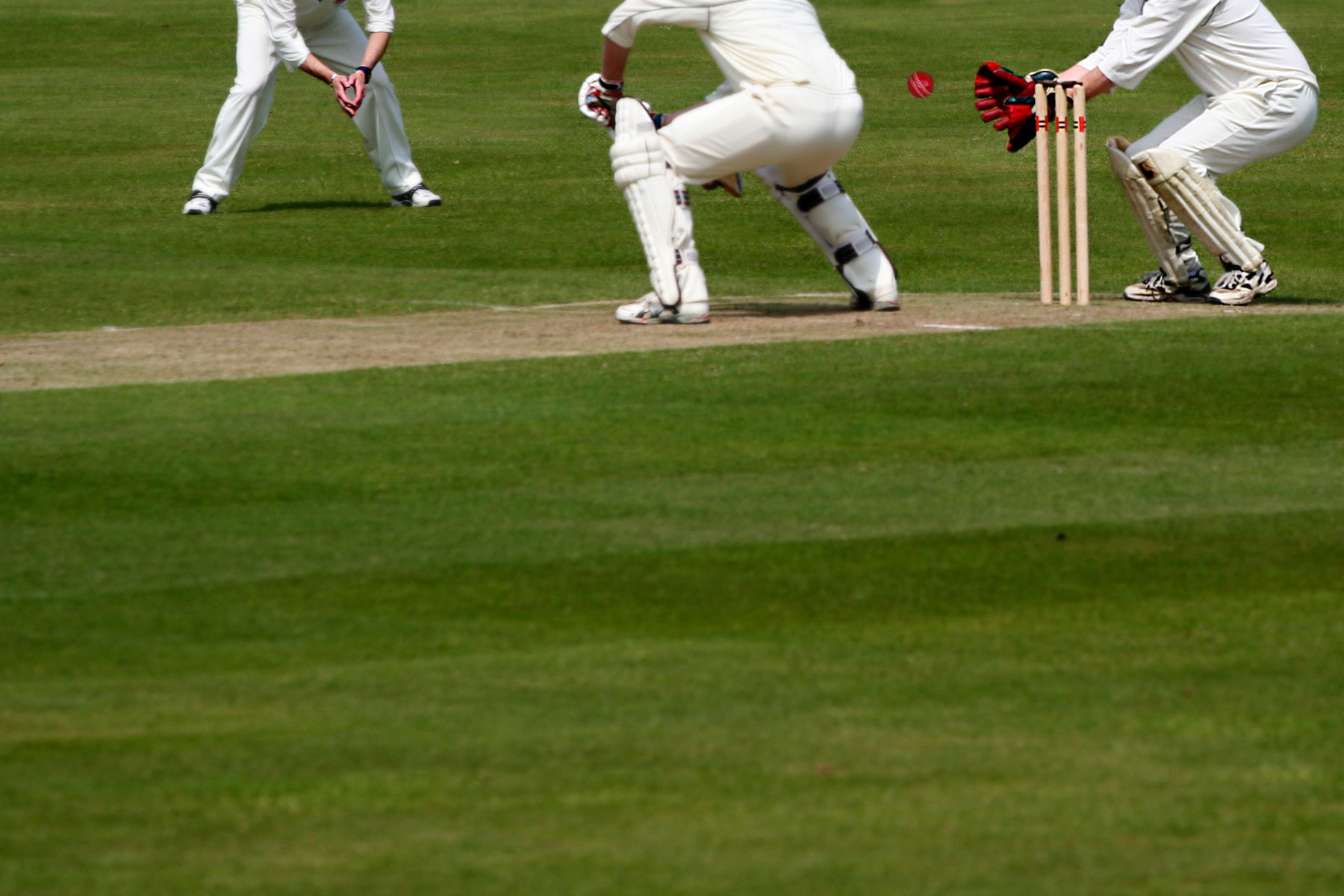 Focus on Cricket Ball which nicks Bat as Wicket Keeper is about to catch out Batsman,with plenty or room for Text