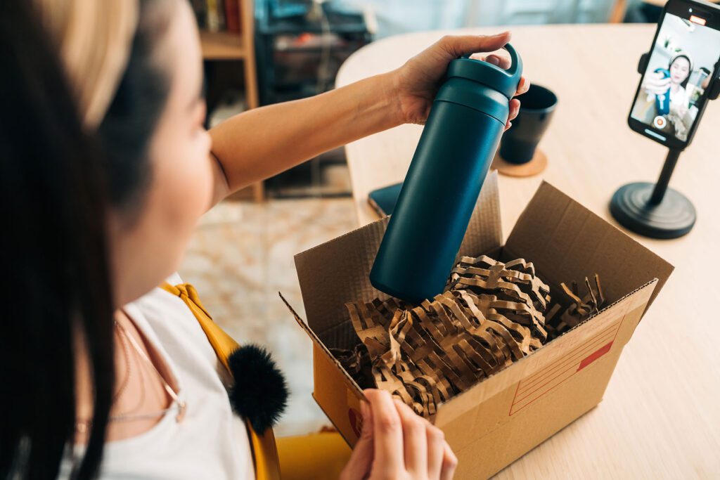 Young woman promoting eco-friendly bottle during live stream