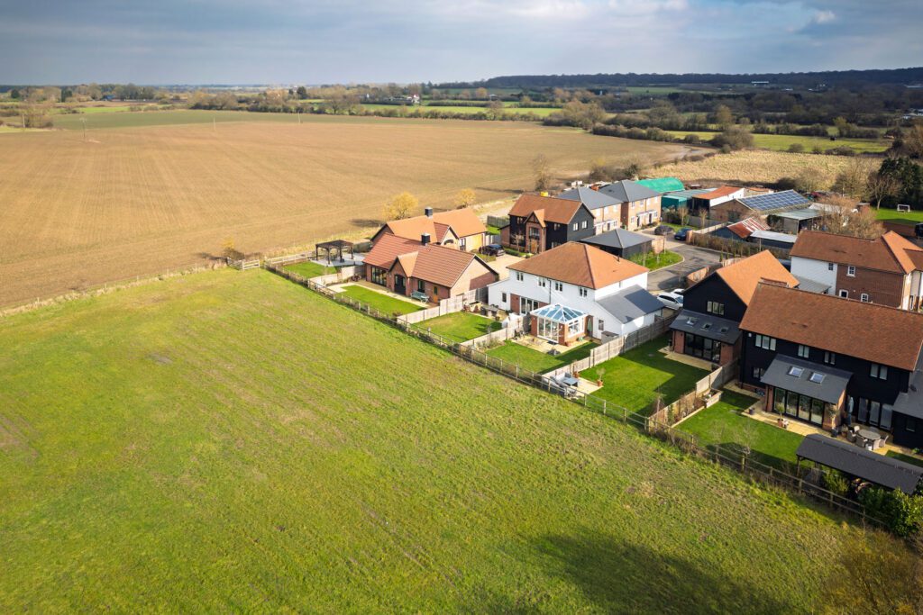 Aerial view of a small estate ofd private houses seen on the edge of rural Essex farmland in the UK. Parcels of land are being sold the housing developers.