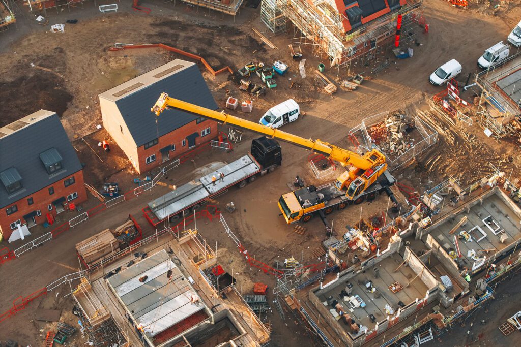 Aerial view of yellow mobile crane at construction site performing lifting operation