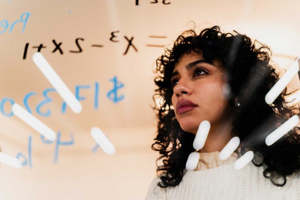Businesswoman planning and looking at math formulas on glass at office
