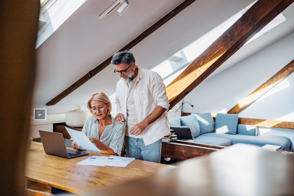 Senior couple reviewing financial documents at home office.