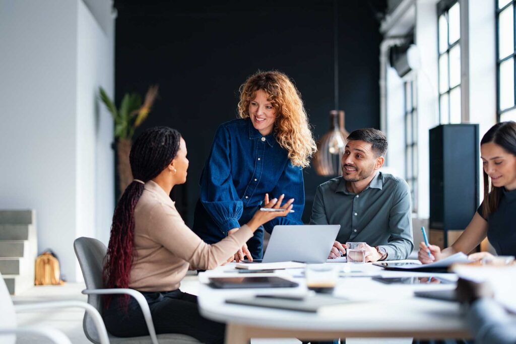 A group of professionals collaboratively discussing projects in a modern office space, showcasing teamwork and productivity with a focus on open communication and strategic planning.